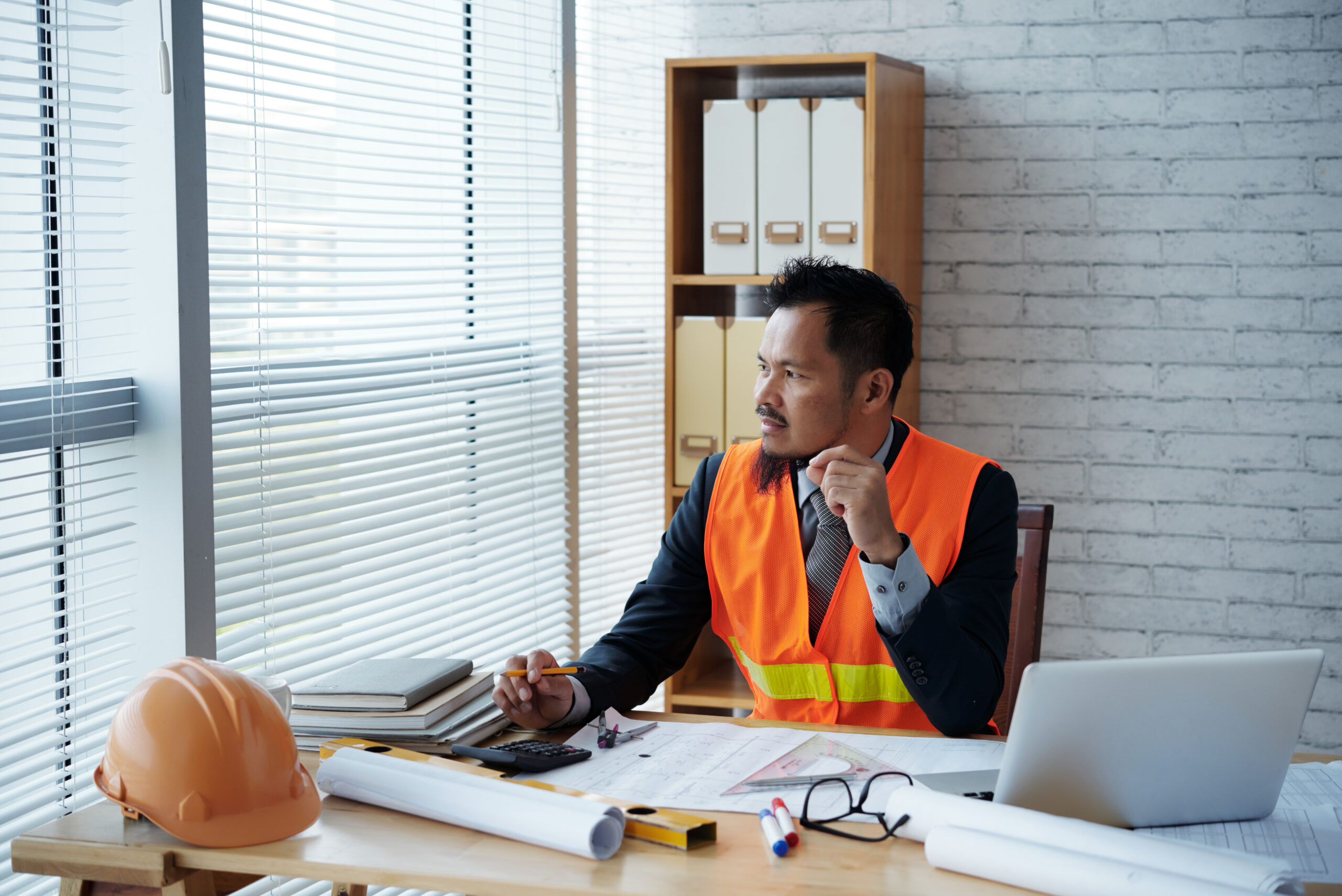 Portrait of pensive Filipino engineer working in his office