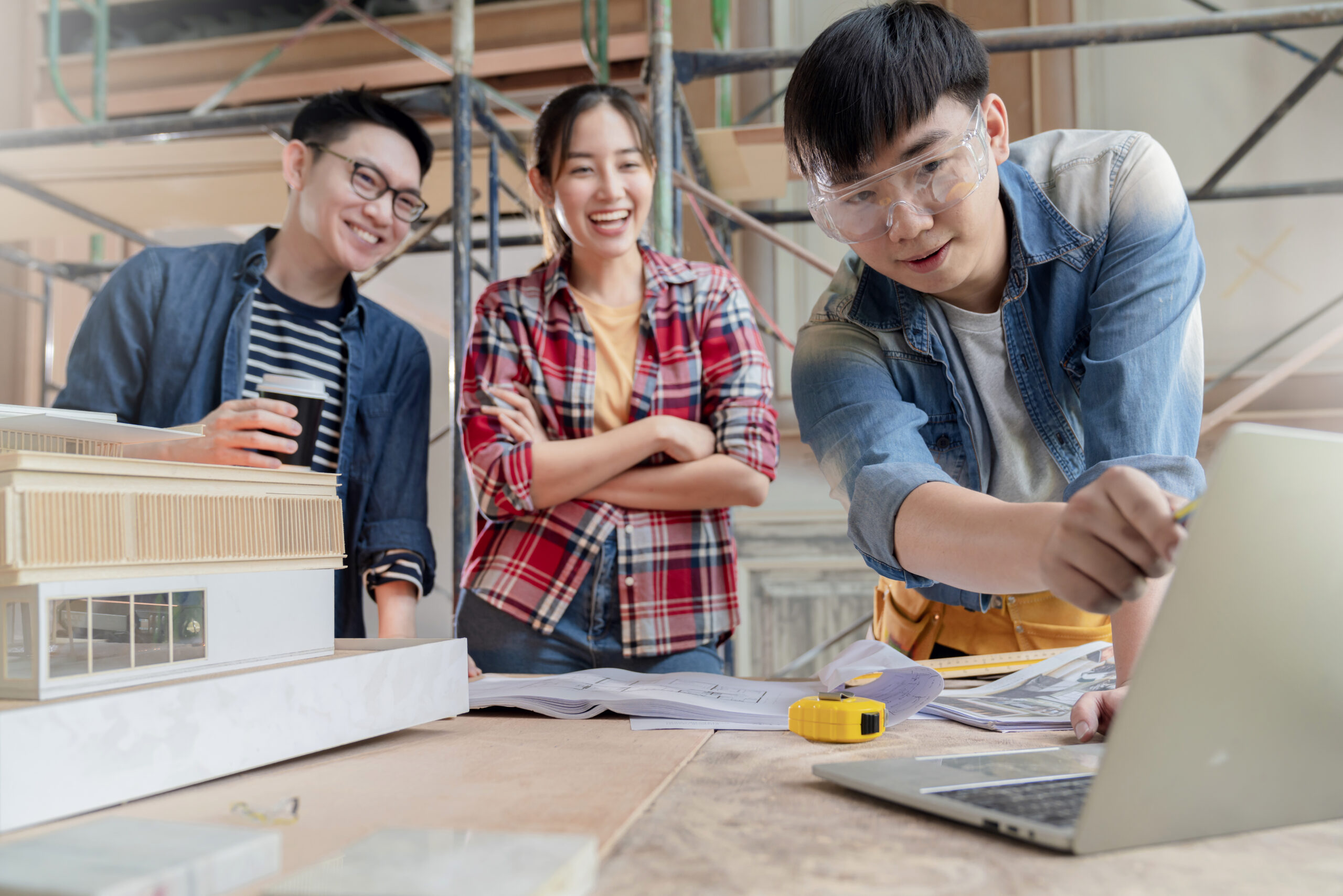group of smart asian architect interior design team consulting with constrction engineer work brainstrom meeting with house project blueprint and home mockup in house renovation structure background
